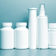 photo of five plastic cans for package pills and vitamins and antiseptic spray for protection against coronavirus KOVID-19 on a blue background. photo without bottle labels