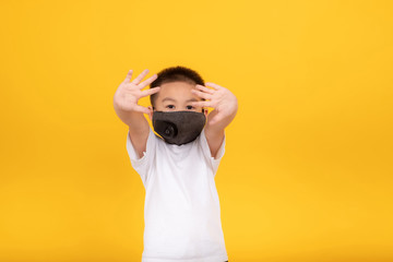 Happy Little asian children boy wearing medical mask protection coronavirus COVID-19 or dust pm2.5 stop gesture hands safety healthy self air pollution concept on yellow background, copy space.