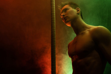 Muscular male circus artist with Cord Lisse on black an smoked background