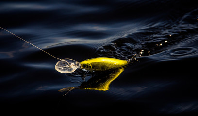 Fishing hook with lure and fishing wire. Dark blue water. 