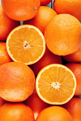 Heap of fresh oranges with half slices