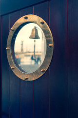 Porthole on a ship with a reflection of a market in glass