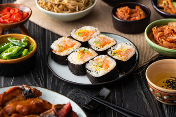 selective focus of gimbap with salmon near chopsticks and korean side dishes