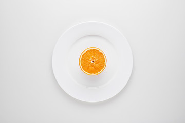 Half slice of orange fruit on white plate with white background