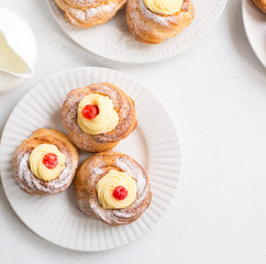 Italian pastry - zeppole di San Giuseppe - baked cream puffs made from choux pastry, filled and decorated with custard cream and cherry. It is eaten to celebrate Saint Joseph's Day.