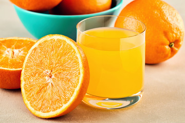 Fresh homemade orange juice in a glass and oranges in a bowl on a table