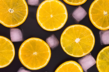 Fototapeta na wymiar Slices of orange and ice cubes on a black background.