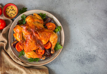 Roasted  chicken with garlic, spices and vegetables: tomatoes and red onions. Top view. Flat lay. Copy space.