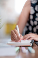 Closeup view of woman hand writing on notebook, vertical view.