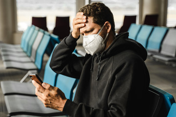 Men with respirator mask sitting in airport. Covid-19 and Air pollution concept.