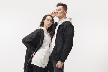 In black. Trendy fashionable couple isolated on white studio background. Caucasian woman and man posing in basic minimal unisex clothes. Concept of relations, fashion, beauty, love. Inclusive.