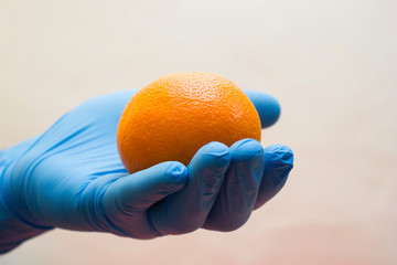 Hand in medical glove holds an orange - vitamin, coronavirus, covid19