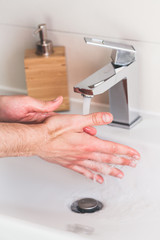 Hand washing with soap in bathroom to prevent contamination, close up