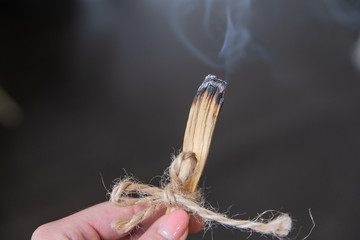 Zbliżenie ręka trzyma palące się drewno. Szamanka używa kadzidło do aromaterapii. 