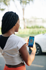 Young woman using car sharing application on smartphone when she needs a ride to city