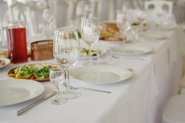 Table setting with wineglasses, plates and cutlery on table, copy space. Place setting at wedding reception. Table served for wedding banquet in restaurant