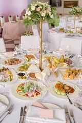 Table setting with blank guest card, white plate with pink napkin, cutlery and flowers on table, copy space. Place setting at wedding reception. Table served for wedding banquet in restaurant