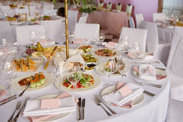 Table setting with blank guest card, white plate with pink napkin and cutlery on table, copy space. Place setting at wedding reception. Table served for wedding banquet in restaurant