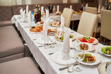 Table set with plates, white serviettes and cutlery on table, copy space. Place setting at wedding reception. Table served for wedding banquet in restaurant