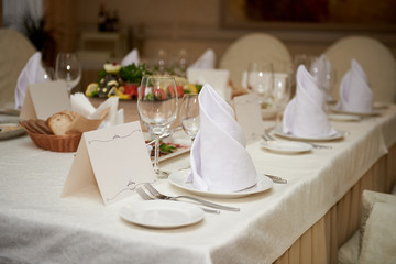 Table set with blank guest card, plate with serviette and cutlery on table, copy space. Place setting at wedding reception. Table served for wedding banquet in restaurant