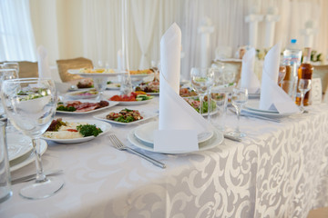 Table set with blank guest card, plate with serviette and cutlery on table, copy space. Place setting at wedding reception. Table served for wedding banquet in restaurant