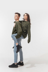 Supporting. Trendy fashionable couple isolated on white studio background. Caucasian woman and man posing in basic minimal unisex clothes. Concept of relations, fashion, beauty, love. Inclusive.