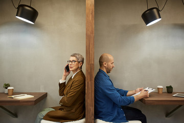 Minimal side view portrait of two adult people separated by wall while sitting in separate cafe booths, copy space - obrazy, fototapety, plakaty