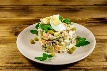 Traditional Russian festive salad Olivier on wooden table