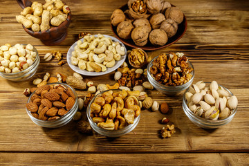Obraz na płótnie Canvas Assortment of nuts on wooden table. Almond, hazelnut, pistachio, peanut, walnut and cashew in small bowls. Healthy eating concept