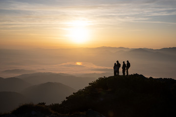 people standing at the hill during sunrise