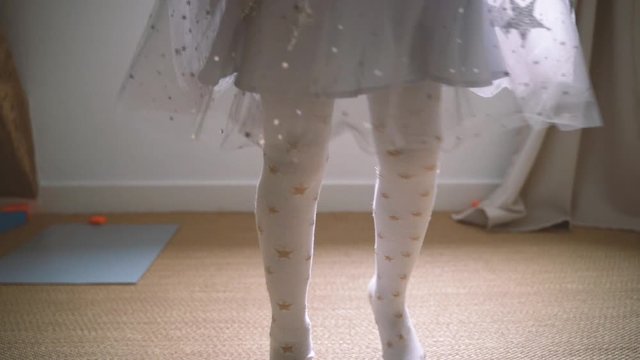 Sweet little girl dancing with happiness and playing at home. Cheerful healthy children. Family lifestyle. Kid dressed like ballet dancer at bedroom with magical light and dreams.
