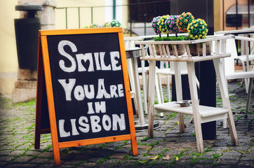 Blackboard with the message Smile you are in Lisbon in the streets of Alfama, historical touristic...