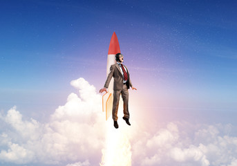 Businessman in aviator hat flying on rocket
