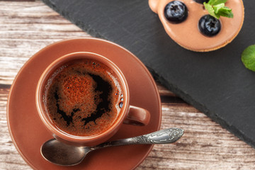 Cup of coffee on the table and a fruit basket on a serving board, fruit muffin with berries
