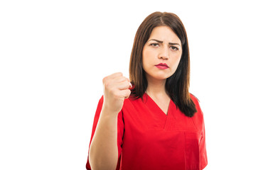 Fototapeta premium Portrait of beautiful young doctor wearing scrubs showing fist