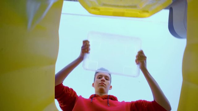 Zero waste. Low Angle View of Young Boy throwing used Bottles into bin and Recycling Plastic. Plastic sorting at home. Collection container with recycling logo. The refuse collection service