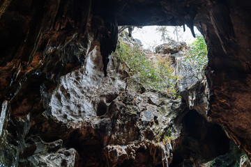 Cave mouth stone isolate on nature background. Inside a dark wet cave with the illuminated hole exit in sight. (Tham Khao Luang Cave at Thailand)