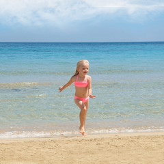 Fototapeta premium Little girl at the beach. Summer vacation concept