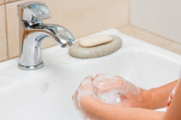 a Washing hands with soap under the faucet with water