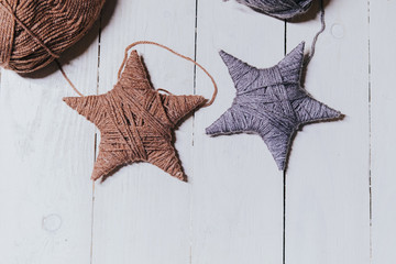 Ball of yarn. Two stars made from worsted lying on a white wooden background, decoration handmade...