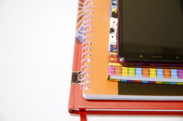  On a white background are multi-colored books, a diary and a smartphone.