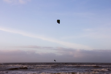 View of the north sea beach on a windy winter day at sunset, people, kitesurfing. Noordwijk, the Netherlands