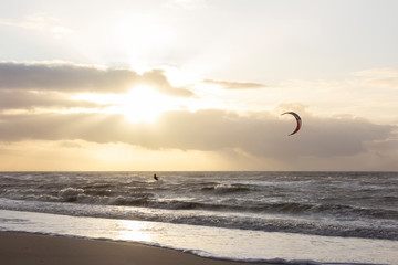 View of the north sea beach on a windy winter day at sunset, people, kitesurfing. Noordwijk, the...