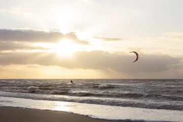 Blick auf den Nordseestrand an einem windigen Wintertag bei Sonnenuntergang, Menschen, Kitesurfen. Noordwijk, Niederlande