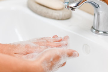 a Washing hands with soap under the faucet with water
