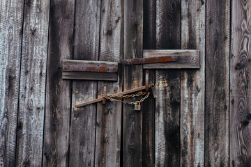 Old wooden barn door with rusty chain and padlock.