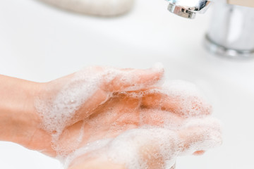 a Washing hands with soap under the faucet with water