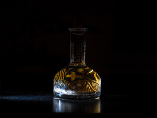 Vintage carafe with homemade vodka on the dark background. Alcoholic drink hrenovuha in transparent...