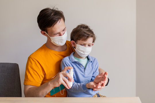 Hand disinfection with an antiseptic. Antibacterial spray sanitation of surfaces from the coronavirus covid-19 virus. Dad teaches his son hygiene. People family in medical masks. Pandemic protection