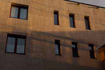 Fototapeta premium Wall of a building with windows. The building is lit by the setting sun.